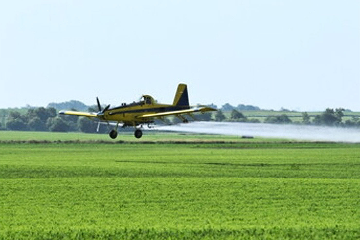 Image of an airplane applying fungicide over a midwestern field